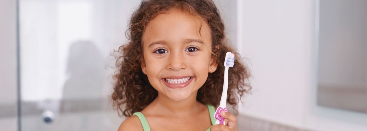 young girl smiling holding tooth brush