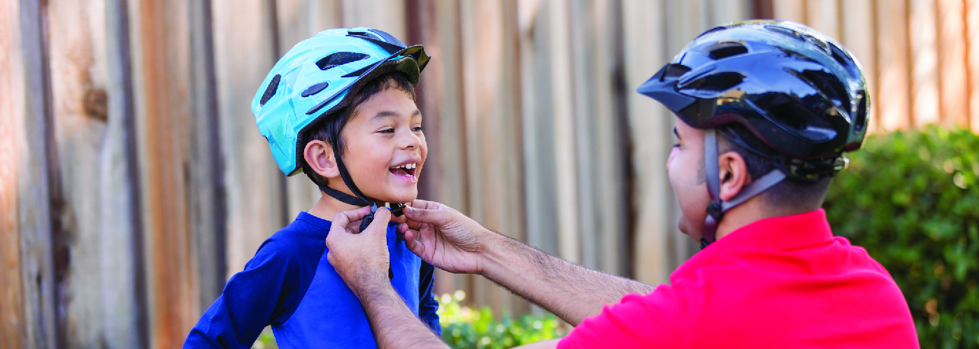 dad putting a bike helmet on his son