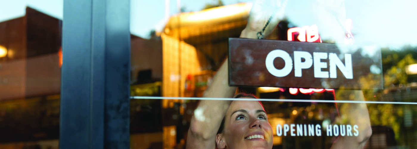 Woman hanging an open sign in restaurant window