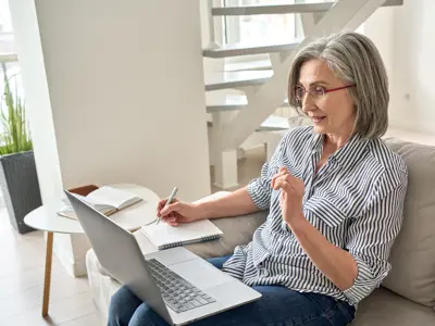 Woman sitting on the couch watching a video on her laptop